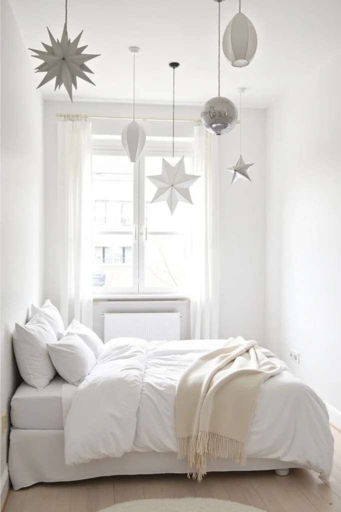 White and silver bedroom with hanging star lanterns and ivory cashmere throw for calm Christmas decor.