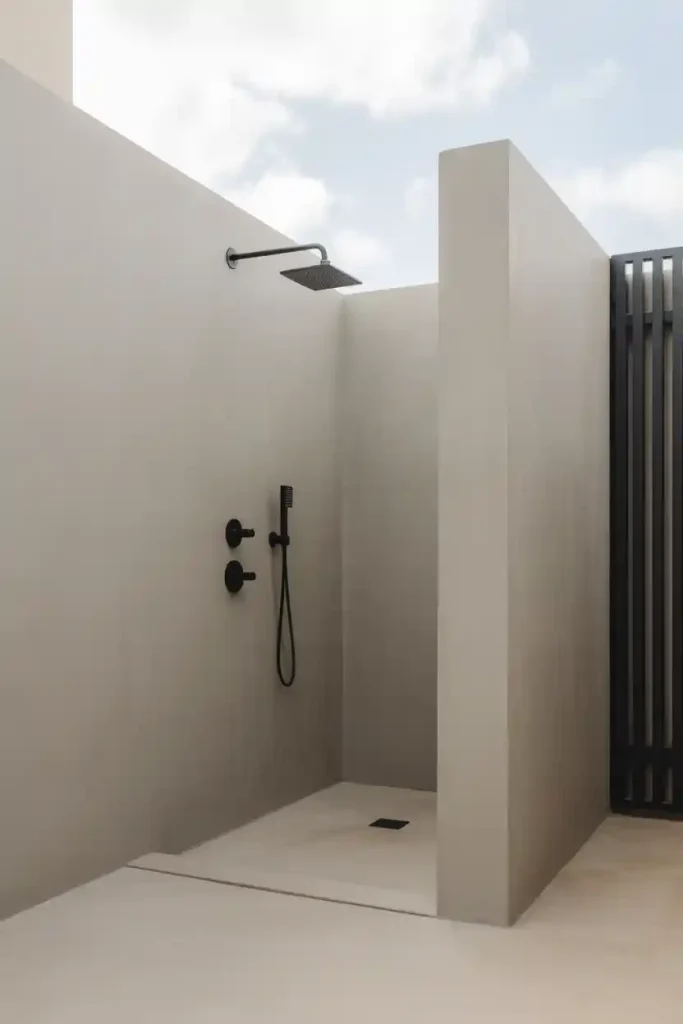 Modern minimalist outdoor shower with black fixtures and concrete wall
