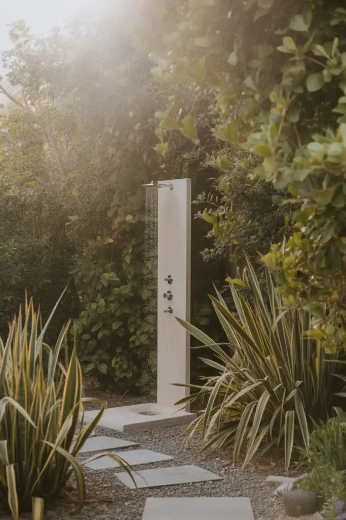 Secluded backyard outdoor shower surrounded by plants and greenery